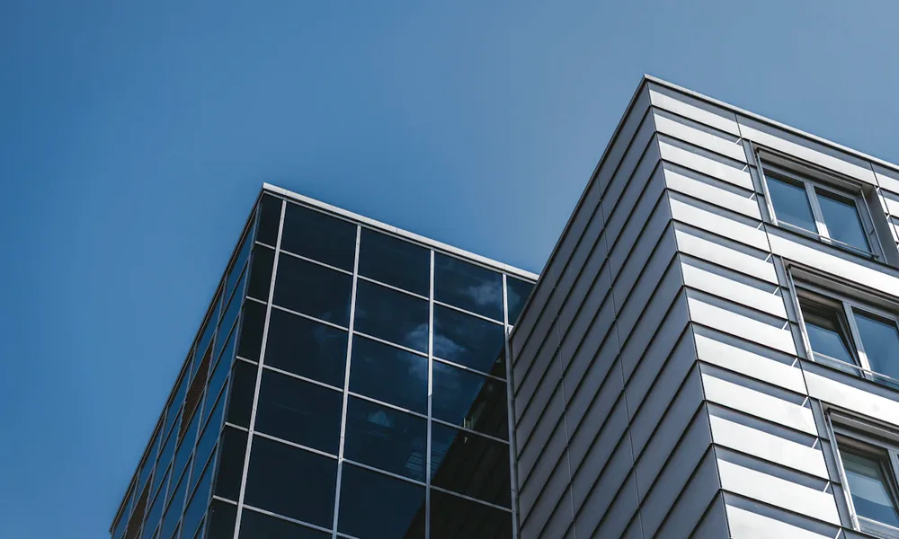 Modern glass-and-metal office building against a clear blue sky
